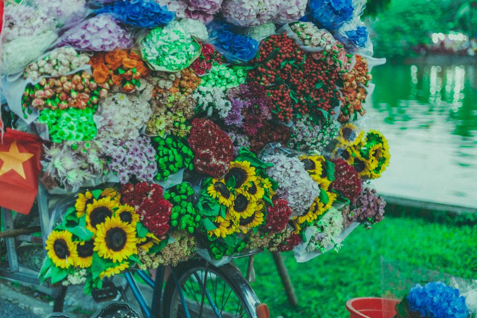 A vibrant display of fresh floral bouquets arranged on a bicycle cart by Norbiton florist for flower delivery. The bouquet includes bright yellow sunflowers with dark centers, surrounded by clusters o